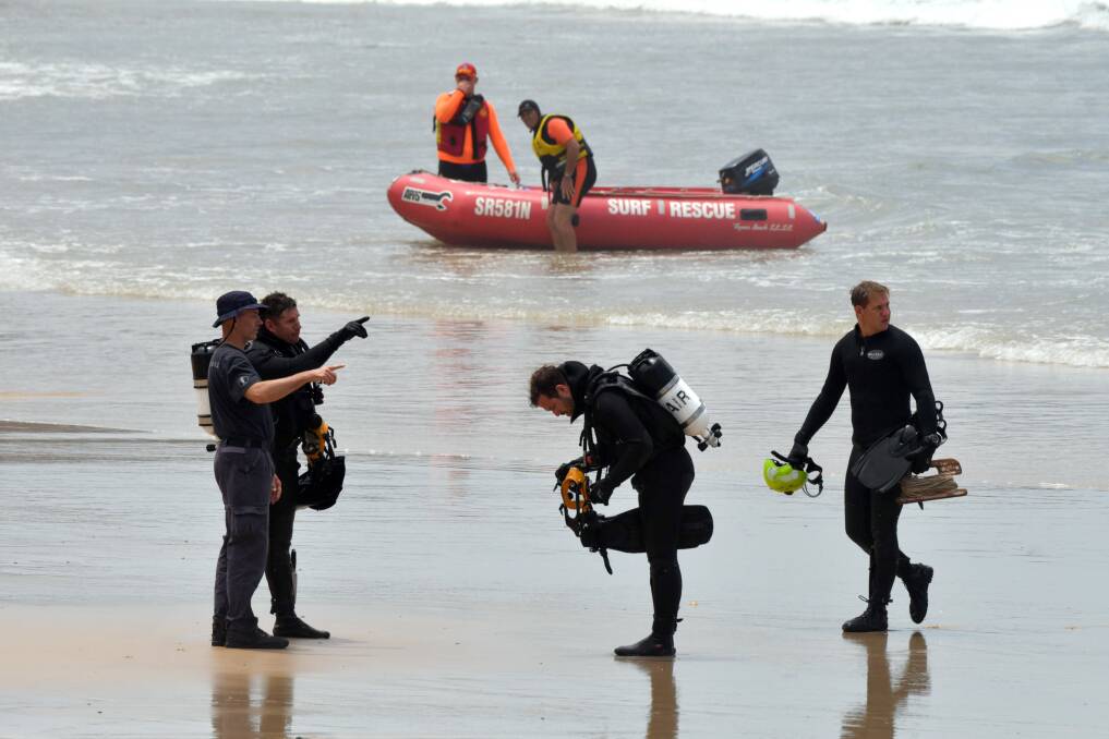 Searching: Divers, surf life saving volunteers and an array of emergency services involved in the retrieval operation for a 14 year old boy swept to sea at Flynns Beach. Photo: Ivan Sajko