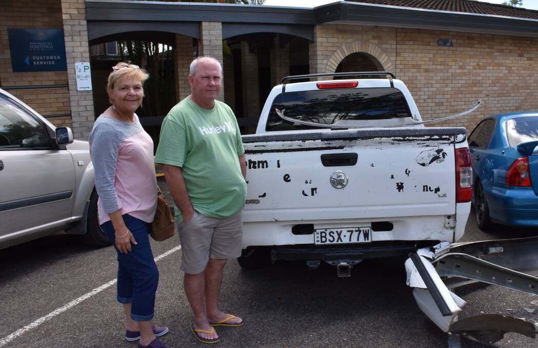 Cherie and Warwick Maltman beside their car outside the library.  The bumper of the car which crashed into theirs is on the ground.