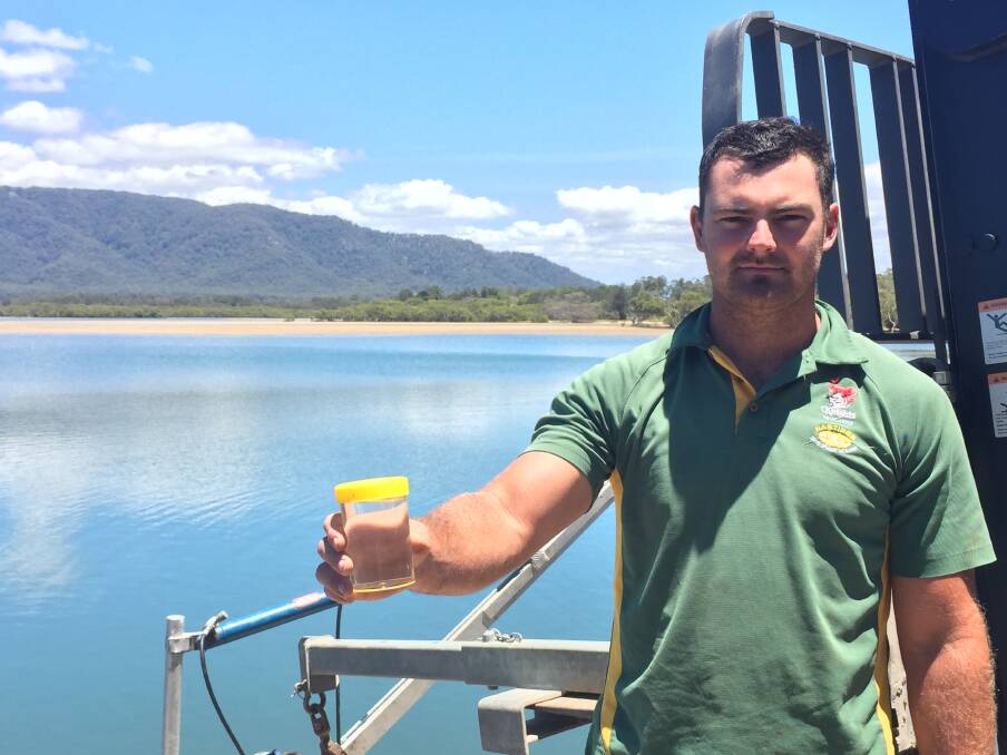 Devastating news: Jack Harper holds a test sample of the river water at the Gogleys Lagoon location for oyster farming. A sewerage pipe burst forced farms to shut down.