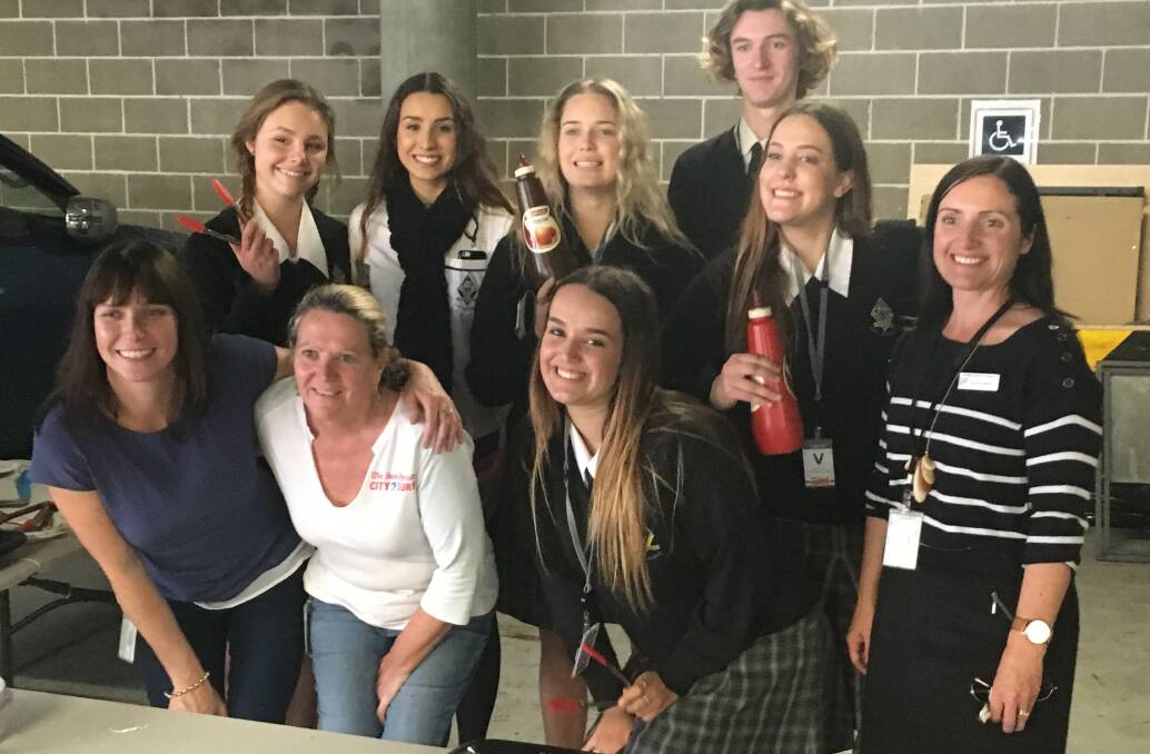 Essential Energy employees Mereki White and Cheryl Adams (front left) with MacKillop College students (back L-R) Zoe Lobb, Lianna Gee, Jordan Gilmour, Noah Smith, Claudia Milligan, teacher Nicole Bailey and (front right) Lani Deutscher at the Grant Street fundraising barbecue. 