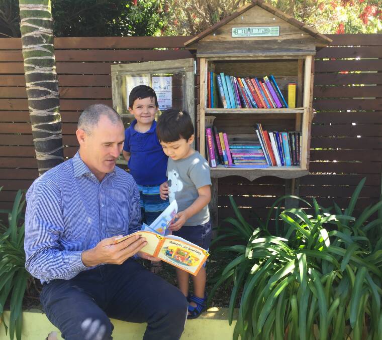 Sense of community: Port Macquarie-Hastings mayor Peter Besseling reads a book from the Street Library on Swift to Jack Slater and Henry Slater.