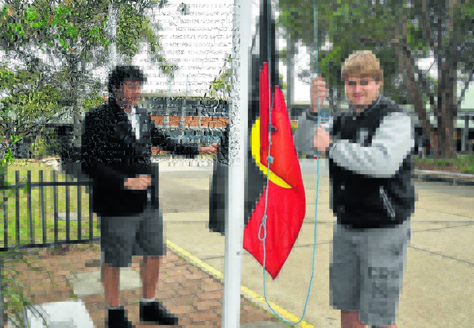 Fly the colours: Port Macquarie High School students Jemaine Wilesmith and Jesse Jones raise the Aboriginal flag in recognition of NAIDOC Week.