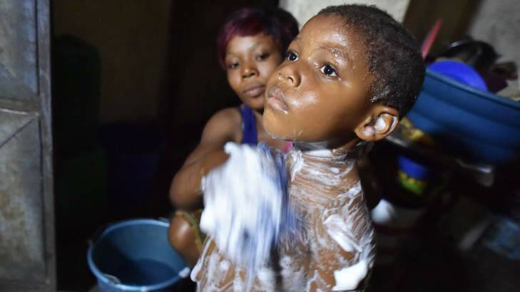A woman washes her child with salted water in a suburb of Abidjan, relying on a rumour that was spread in the area claiming that salted water helps to fight against the Ebola virus. Photo: AFP Photo