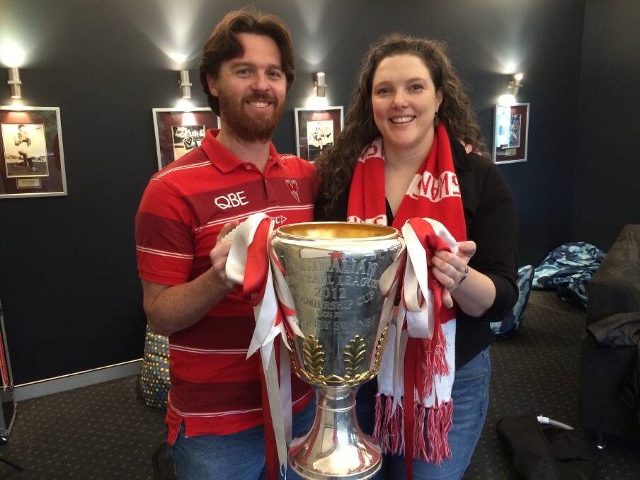 Their cup runneth over: Mark Headon and Kathryn Johnston hold onto the coveted AFL Championship trophy won by the Sydney Swans in 2012 as they prepare for their wedding at the SCG tomorrow.