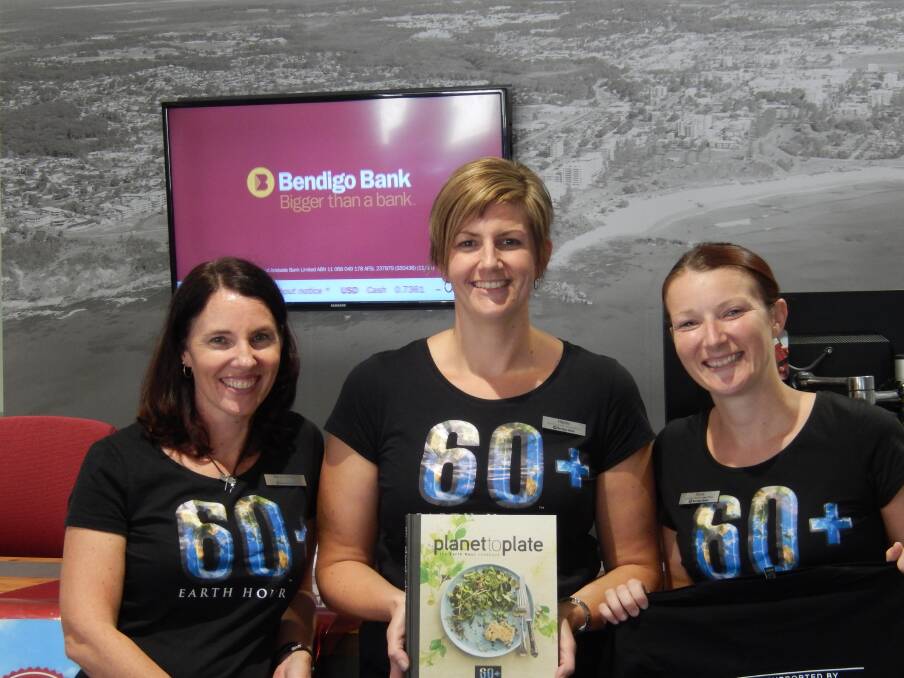 Turn darkness into light: Bendigo Bank branch manager Kerry Lumby, senior customer service officer Hayley Owen, and customer relationship officer Alicia Dewberry with a copy of the Earth Hour cookbook Planet to Plate featuring recipes by Australia's top chefs.