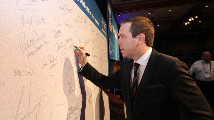 AWU chief Paul Howes signs his name to a pledge to stop Tony Abbott in his tracks at the union's conference in Queensland.
