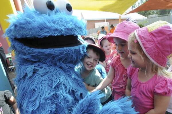 Sesame Street's Cookie Monster is bombarded with hugs by Bodhi Johnson, Brianna Waller and Taylee Miller at the Lighthouse Child Care Centre.