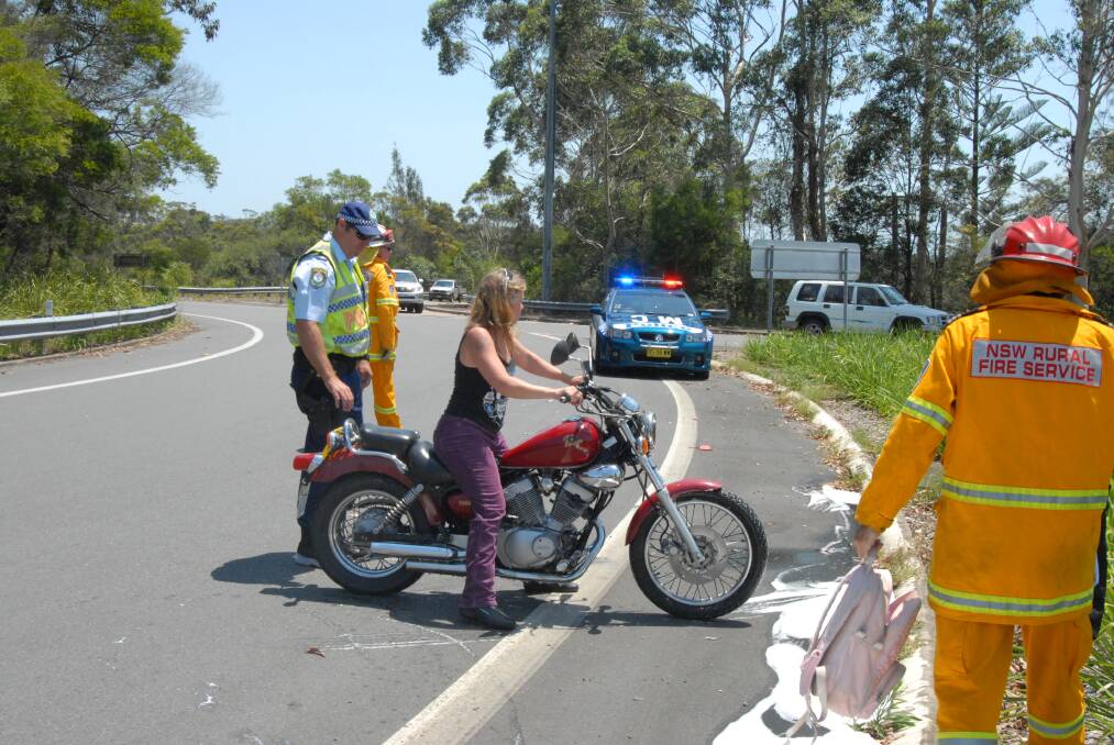 The woman moves her damaged bike off the road.