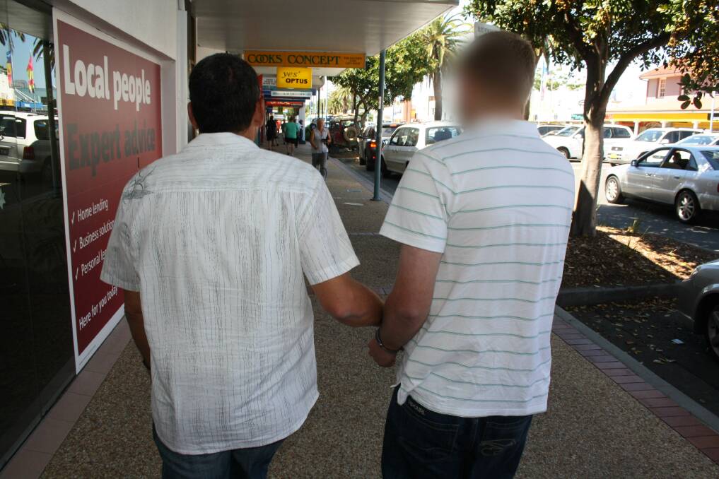 Exploitation: A detective (left) leads away the 34-year-old man in Port Macquarie’s CBD after he was arrested yesterday for offences relating to child grooming.