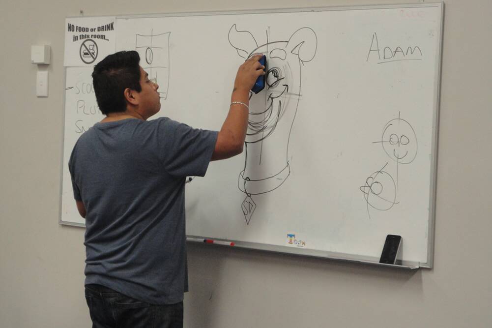 Adam Brisson shows youngsters how to draw  using cartoon style figures.