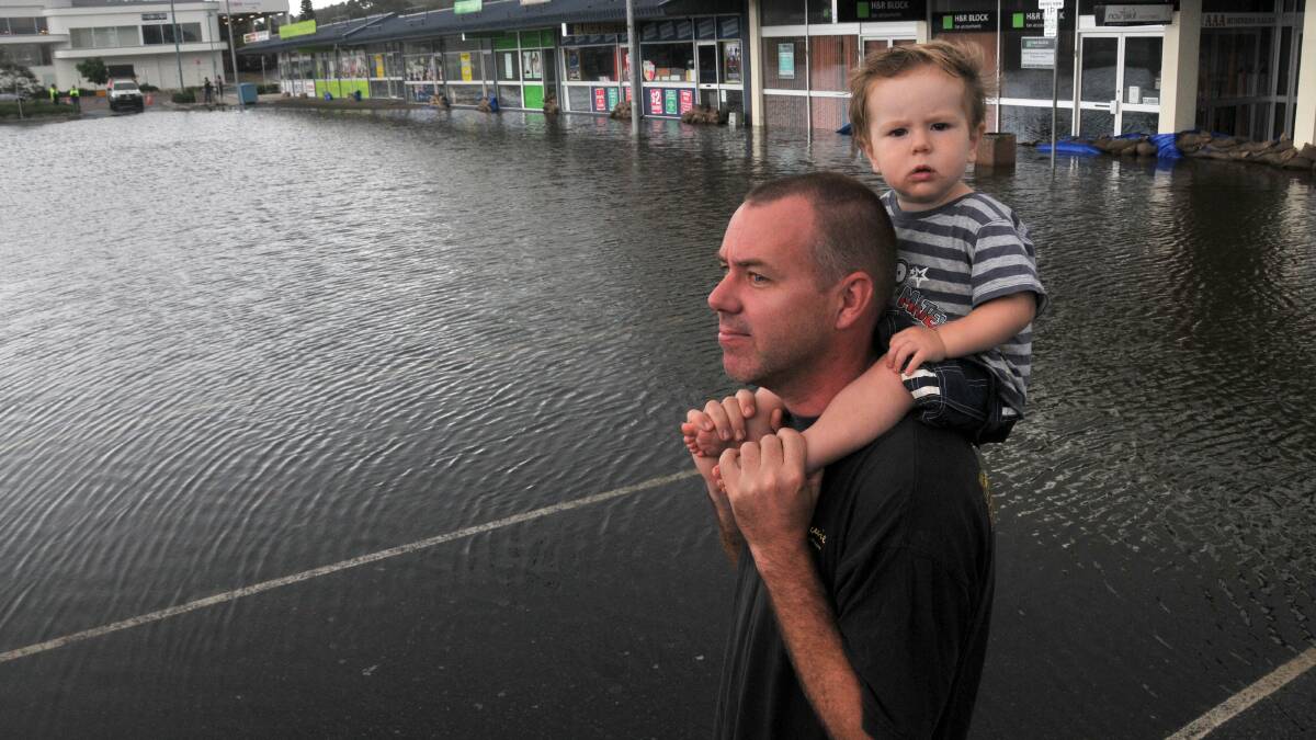 Craig Suosaaro checks out the flooding in Short Street with his 15-month-old son Alexander.
