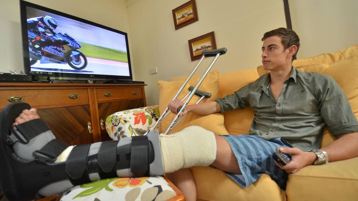 Broken leg for lending a hand: Jonathan Hadley convalesces at home watching motorbike racing after he and his motorcycle were hit by a car when he stopped to protect a koala on Lake Road.