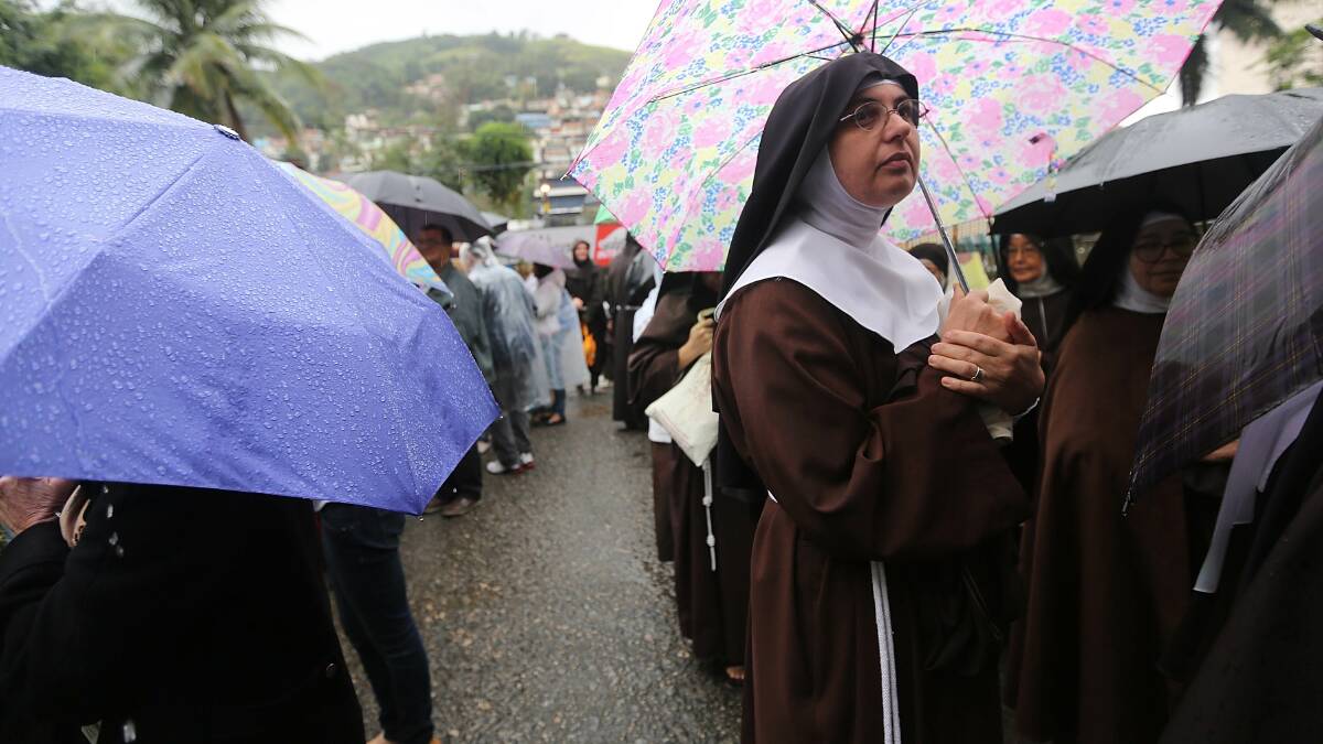 Nuns from the Nossa Senhora dos Anjos monastery (R) wait in line in the rain to attend Pope Francis' visit to the Hospital de Sao Francisco de Assis (Hospital of Saint Francis of Assisi) on July 24. Photo: Getty Images