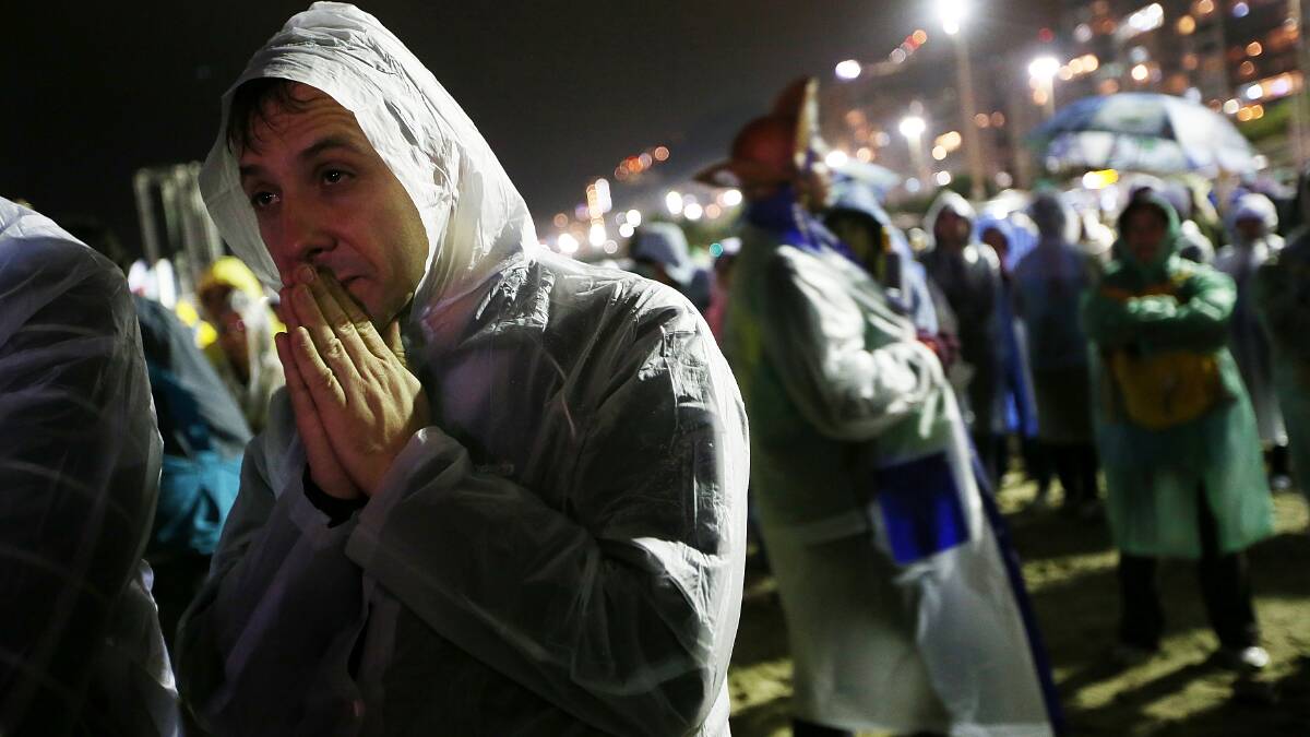 People gather in the rain as Pope Francis celebrates Mass on Copacabana Beach on July 25. Photo: Getty Images