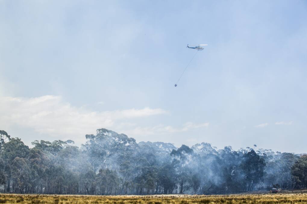 A water bombing helicopters work to control bushfire next to the Kings Highway near Bungendore. January 9, 2013. Photo: Rohan Thomson.