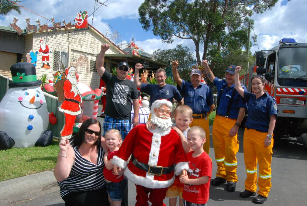 IN THE CHRISTMAS SPIRIT: (back row) Paul Judd with volunteer fire fighters Thomas O’Byrne, Frank Vrbanc and Mick and Katie Reeve. (front) Lisa, Laura, 2, Matthew, 5, and Riley Judd, 4 out the front of the Manning Lane residences which have been decorated for Christmas. Any donations received will go towards the Tuncurry Rural Fire Brigade. Photo:The Great Lakes Advocate.