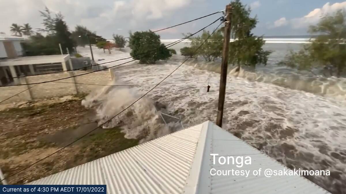 A tsunami crashes through a fence in Tonga after the Hunga Tonga-Hunga Ha'apai volcano erupted at 3.10pm AEST on Saturday, January 17. 