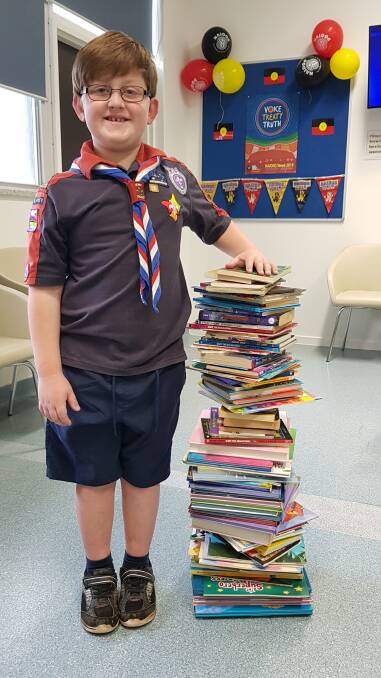 Well read: Seven-year-old Oliver Whatmough with the mountain of books he collected for the Speech Pathology Team's Book Box.