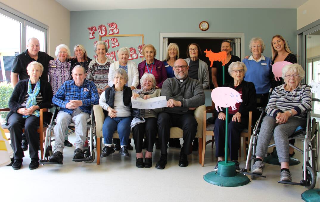 Helping out: St Agnes’ Parish Priest, Father Paul Gooley accepting a donation to the Bale Out Appeal from residents and staff of the Catholic Care of the Aged Care facilities.