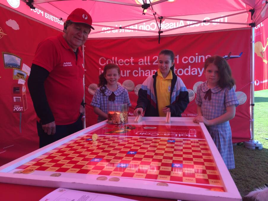 Coin hunt: King Creek's Jessica, Keira and Jordan Trembath testing their skills on the roll-a-coin as Australia Post's Ross Sewell looks on.