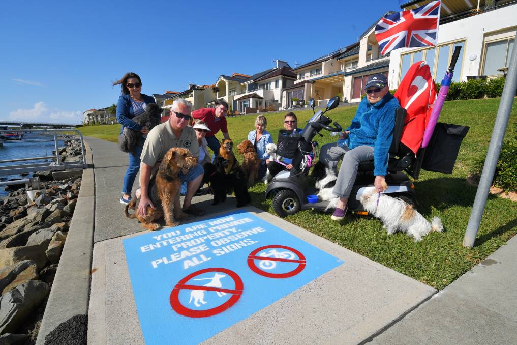It's a dog fight: Broadwater Canal residents - and their pooches - Anita Abel (Teddy), Mick Goodwin (bruce), Helga Collins (Haley and Sasha), Andrew Crane (C.J), Helen McGee (Frankie), Rob Brusdon (Macca) and Sheila Wick (Poppy and Tinker) are up in arms over upgraded signage prohibiting dogs and bikes from footpaths in the precinct. Photo: Ivan Sajko