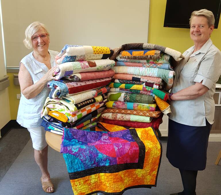 HEART-WARMING: Wauchope Patchwork Quilters president Helen Clunas and Palliative Care Nurse Unit Manager Mary Trotter with some of the beautiful works of art donated by quilters from all over Australia.