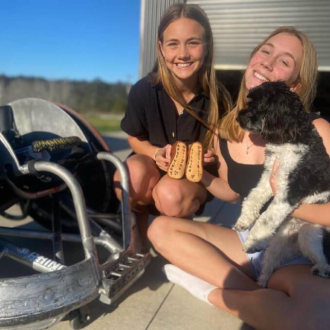 Taste of home: Lily and Aaliyah Batt with the pair of baby boots inscribed with their names and 'Anything's Possible' that will sit under dad Ryley's wheelchair at the Paralympics.