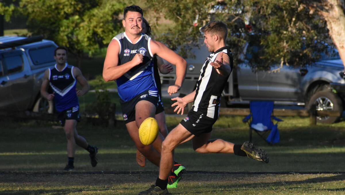 Boot to ball: Port Macquarie's Kye Taylor gets a kick away despite the oncoming attention of a Northern Beaches opponent. Photo: Green Shoots Marketing
