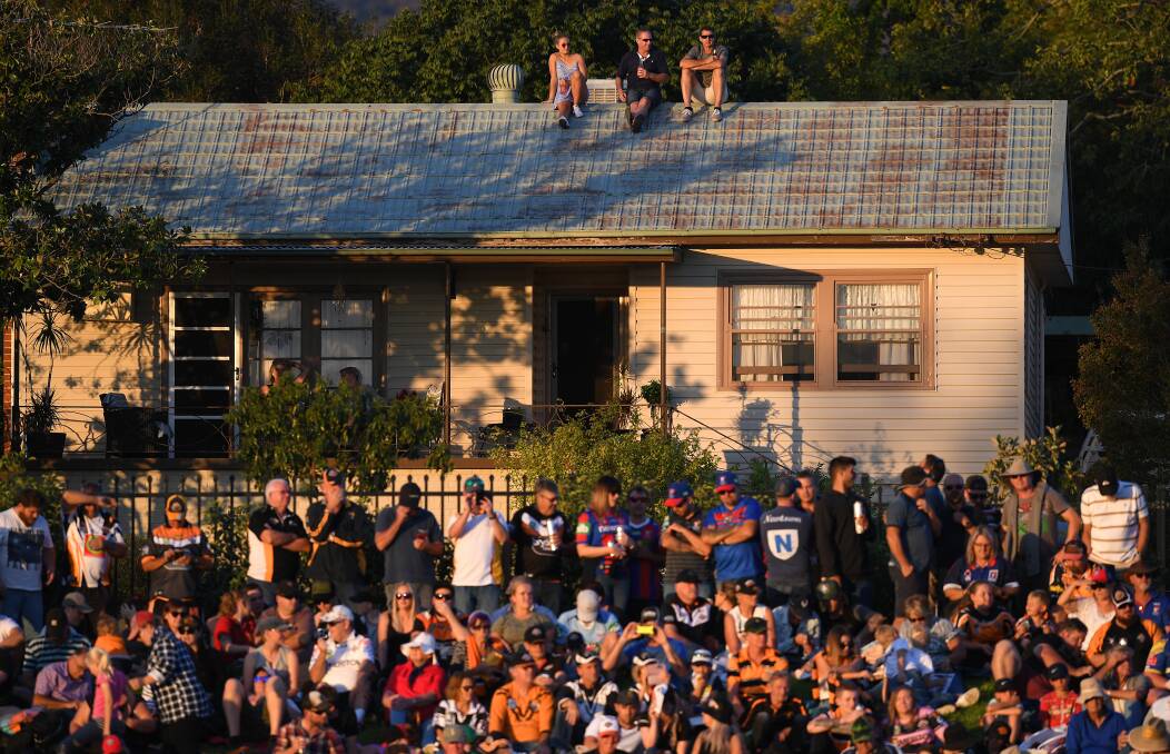 Spectators are seen watching on from the roof of a house during the Round 7 NRL match between the Wests Tigers and the Newcastle Knights at Scully Park in Tamworth, Saturday, April 21, 2018. (AAP Image/Dan Himbrechts) NO ARCHIVING, EDITORIAL USE ONLY