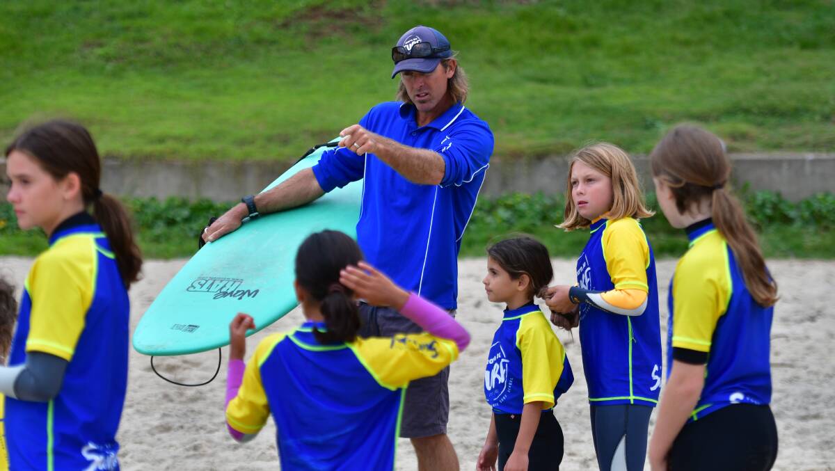 Good to go: Wayne Hudson offers some coaching advice to his surf school students at Flynns Beach on Monday. Photo: Paul Jobber