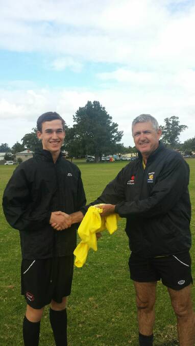 FMNC assistant referee coach Rodney Dobson presenting 18 year old Charles Adnum with a new shirt ahead of his first grade centre debut recently.