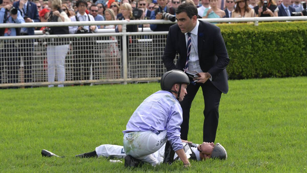 Jockey Glyn Schofield attends to Andrew Adkins after a horror fall at the finish line, during the Kings Of Sydney Sport Mile during The Championships. Photo: AAP/Simon Bullard