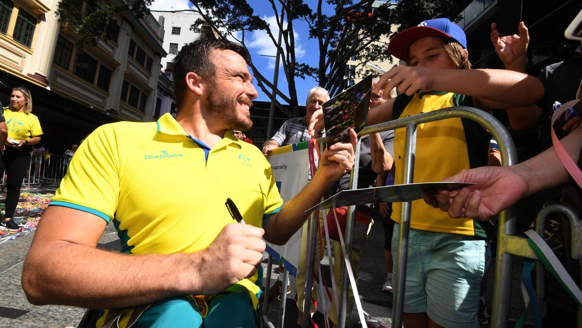 Commonwealth Games wheelchair race gold medalist Kurt Fearnley signs autographs during a street parade to honour the games' athletes through central Brisbane, Friday, April 27, 2018. (AAP Image/Dan Peled)