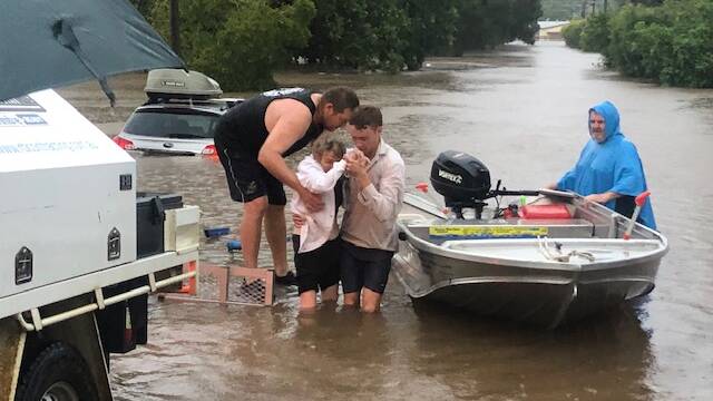 An elderly woman is helped to safety from rising floodwaters in Lismore. Picture: Rod Harris