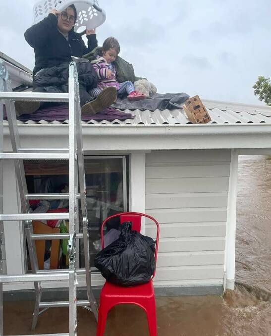 Mother Jess Rankin takes shelter from the floods beneath a washing basket on the roof of her South Lismore house. Picture: Supplied