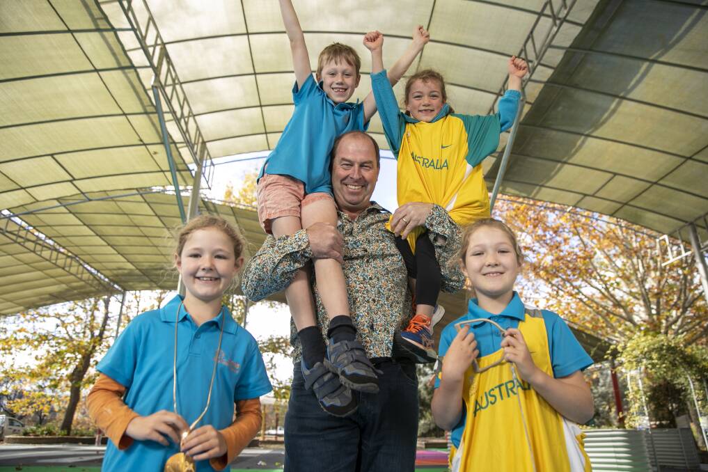 Stuart Rendell, a retired hammer thrower who is now the deputy principal at Lyons Early Childhood School, shows his medals and memorabilia from Olympic and Commonwealth Games competitions with students Asher Barclay, Sam Williams, Evie Reilly and Ellie Barclay. Picture: Keegan Carroll
