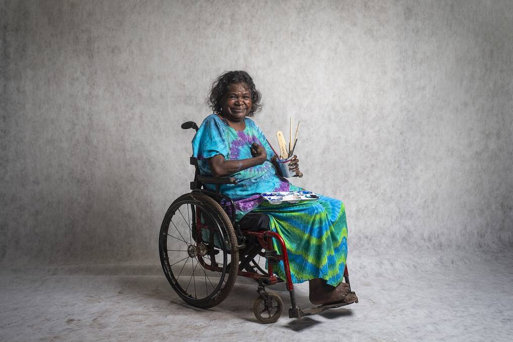 ART JOURNEY: Dhambit Mununggurr has been painting in her signature blue acrylic for only a few years, after a car accident in 2007 left her with serious brain damage and almost took her life. Image: Rhett Hammerton/NGV