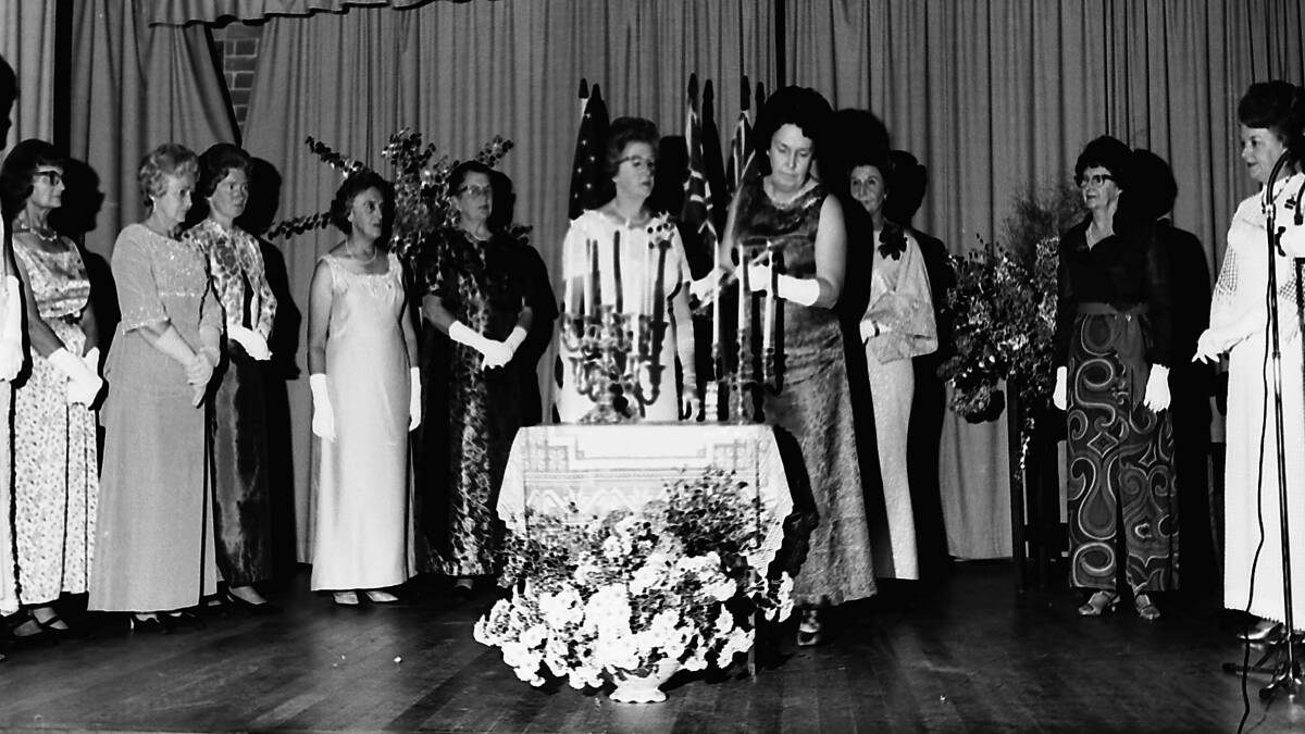 Ceremony: Visiting Quotarian, Lorna Slack watches Joy Jensen light her candle surrounded by other members at the Installation Dinner, 1969.