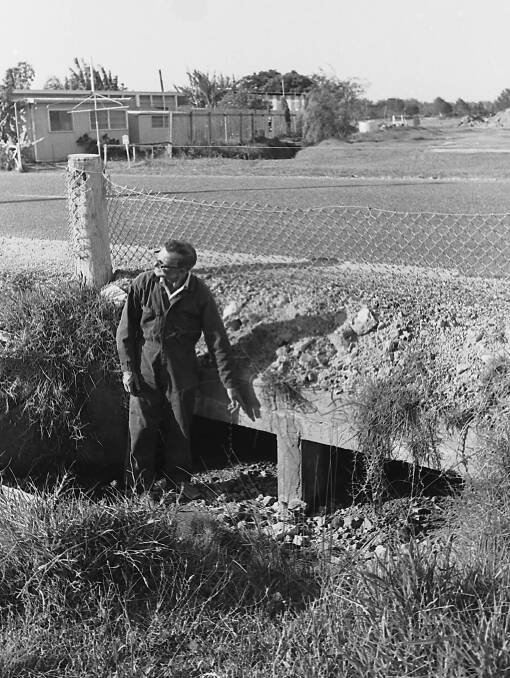  Rennie Dick, president, of the Hibbard Progress Association points out the only culvert on Hastings River Drive, 1971.