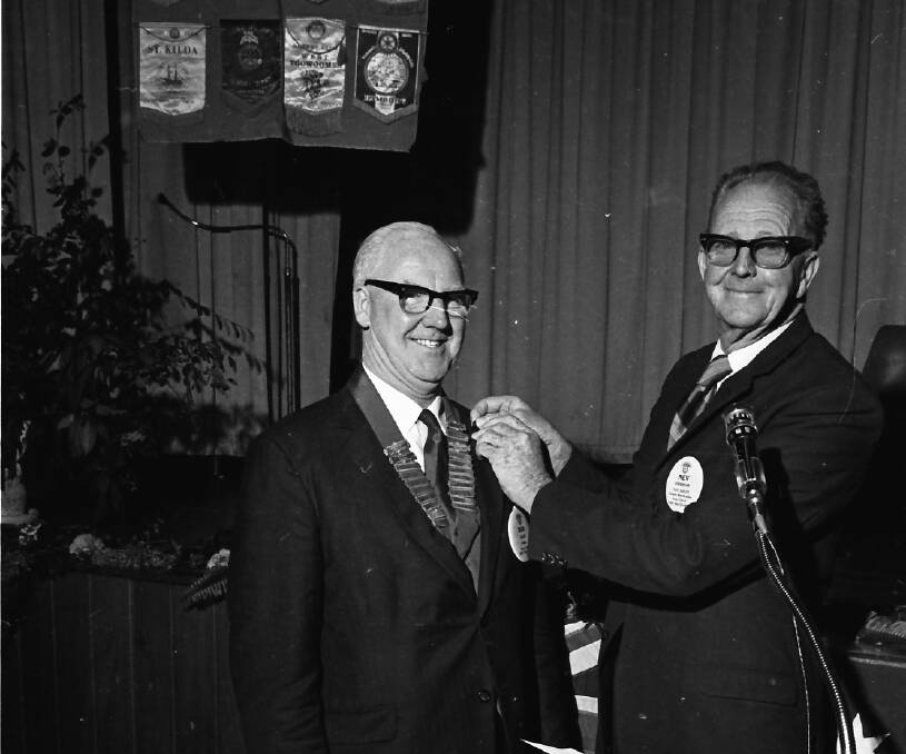 Neville Anderson gives his badge of office to incoming president, Reverend R J Allan.