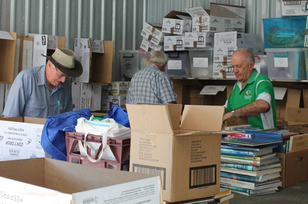 HARD AT WORK: Laurieton Rotarians hard at work sorting the books.