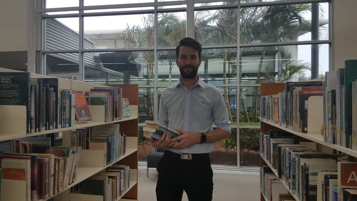 FUN: Port Macquarie librarian Brandon MacDonald among the books. Photo: Laura Telford.