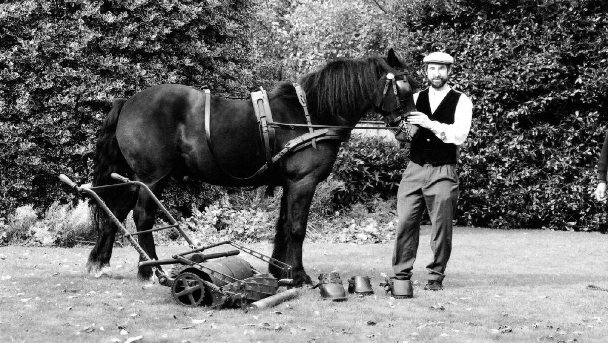 In the moment: Museum Curator Brian Radam posed for this black and white publicity shot with a century-old horse-drawn lawnmower.