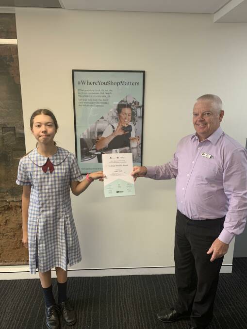 Newcastle Permanent's Adam Power presents Lucy King from St Columba Anglican School who won the year 5 District Award.
