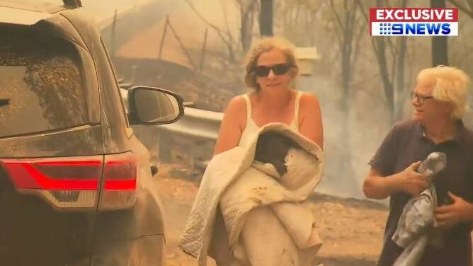 Toni and Peter Doherty emerge fro the fire zone with little koala Lewis. Photo: 9News.