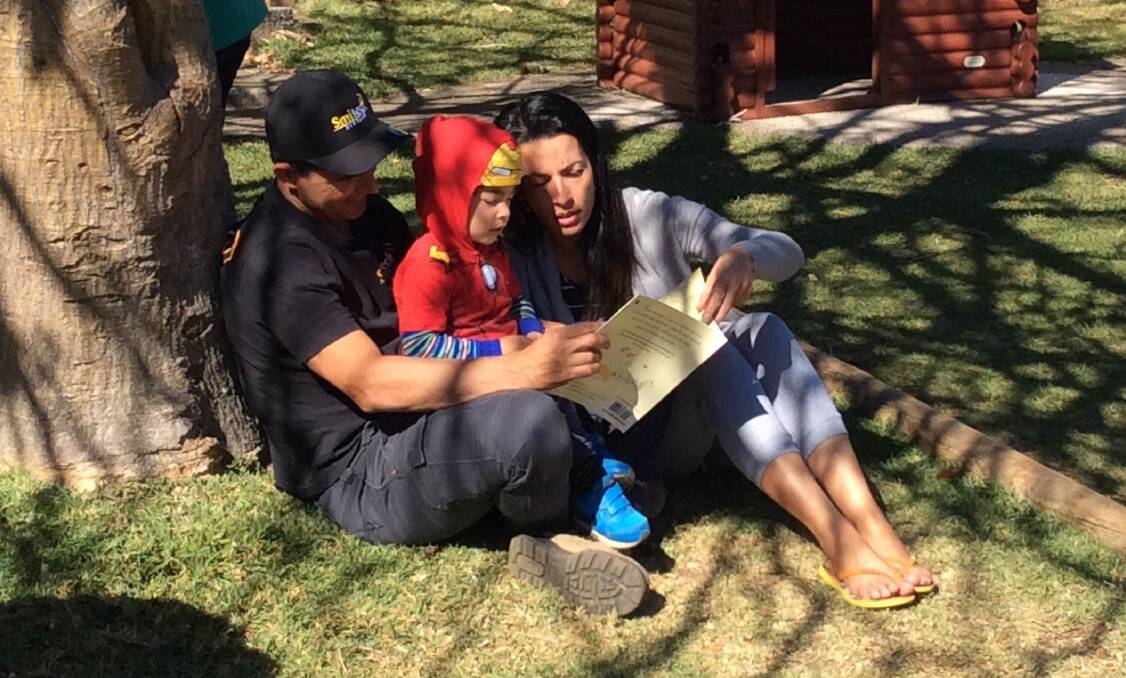 Gui enjoyed a story in the shade with his mum and dad.