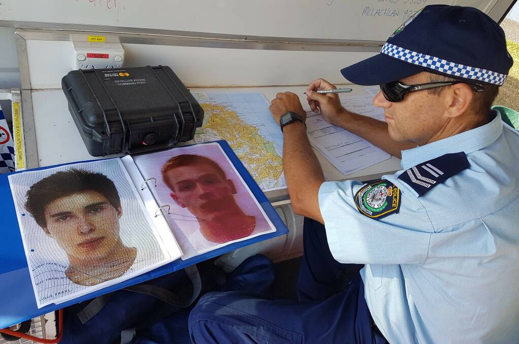 Leading Senior Constable Tim Williams with photos of the missing men in Port Macquarie.