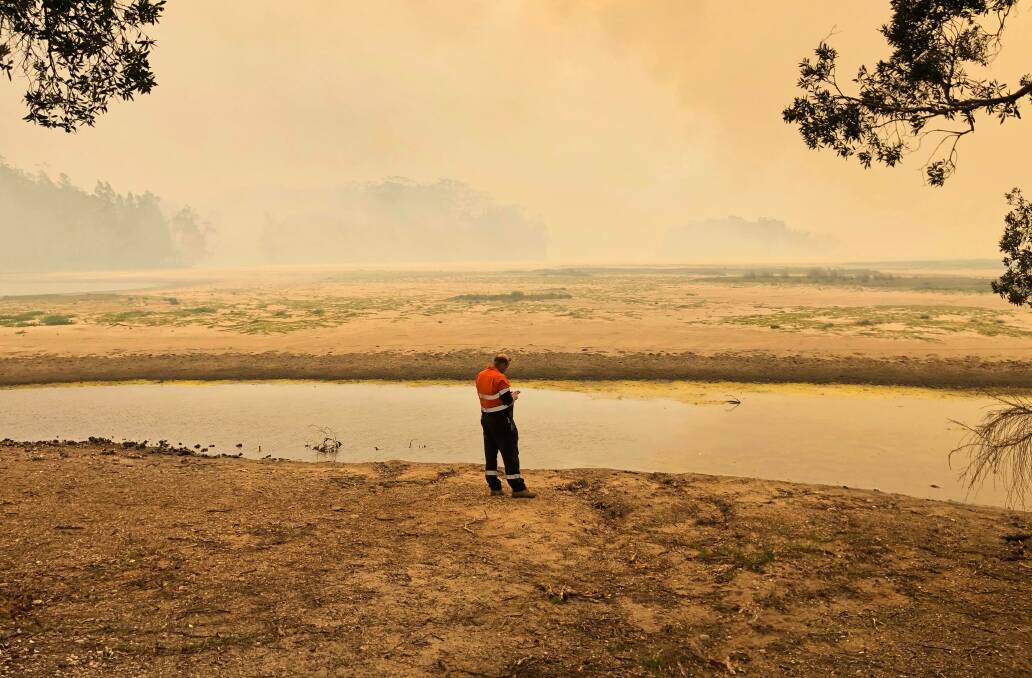 Ben Carey at the lake. Fire is burning on some parts of the lake where water once was. Photo: Lisa Willows.