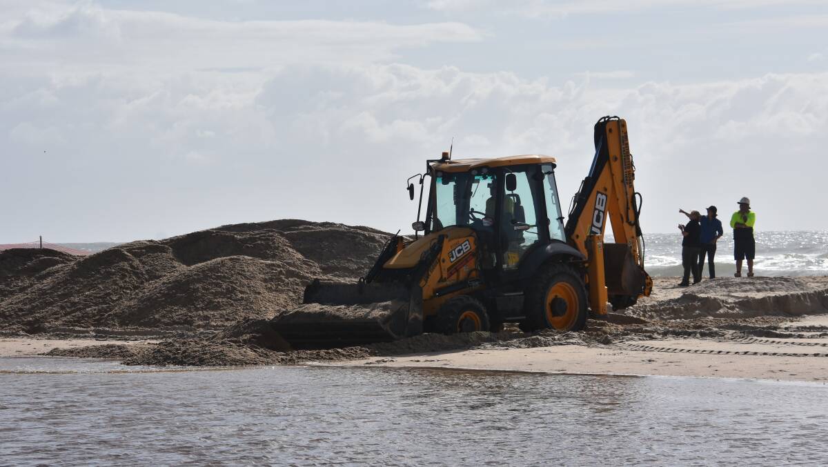 ON THE JOB: Excavator scraping away the sand berm near Lake Cathie.
