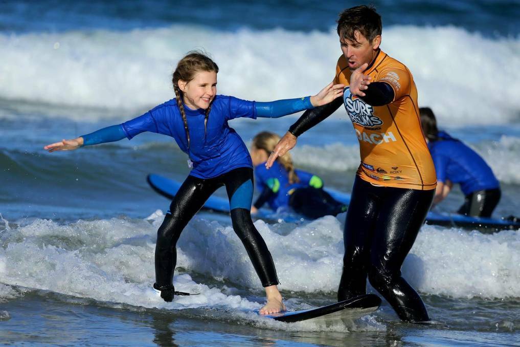 FUN IN THE WAVES: Kitty Duffy learns her craft from surf coach Wayne Hudson in 2017.